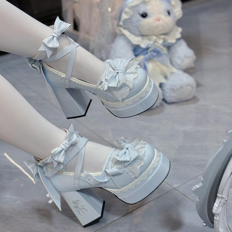 White high-heeled shoes with decorative bows and lace details on a reflective surface.